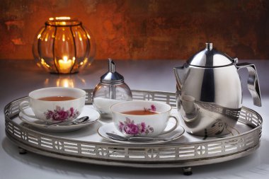 Paslanmaz çelik çaydanlığı, eski Hollanda çay fincanları ve paslı bir duvarın önündeki tepside duran şeker kutusu olan iki kişiye özel kaliteli çay.