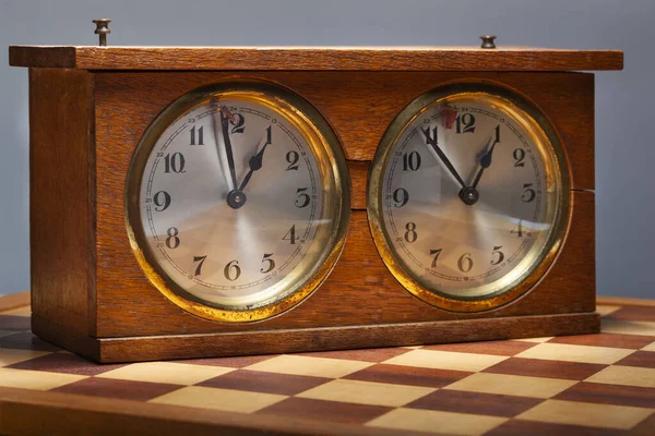 Old wooden vintage chess clock and a chessboard