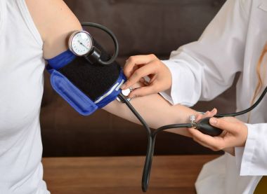 Bir kadın doktor hasta masada kan basıncı kontrol Resim kırpılmış         