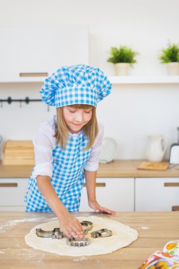 Sevimli küçük kız tarafından bir pasta teneke bir hamur bir tablo üzerinde iter
