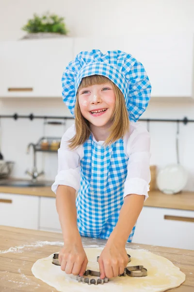 La bambina sorridente spinge da una scatola di torta su una pasta su un tavolo — Foto Stock