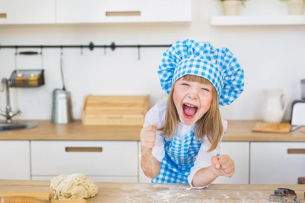 Ritratto di bella bambina in un cuoco sembra divertente urla una cucina — Foto Stock