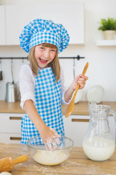Ritratto di una bambina in abiti da cuoco vicino a un latte e un impasto in una ciotola — Foto Stock