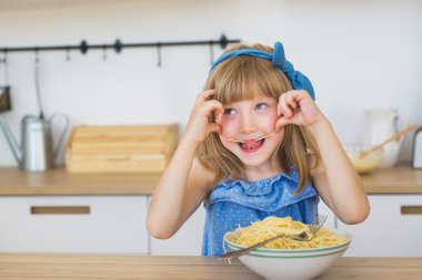 Küçük kız komik portresi bir spagetti bir yemek yiyor ve bir dilini koyar