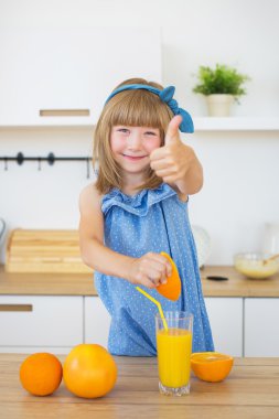 Sevimli küçük kız mavi elbise basın bir portakal ve gösteri gibi