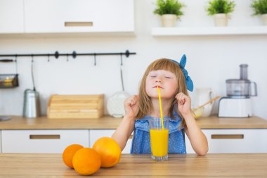 Küçük kız komik portresi bir masanın üzerine taze meyve suyu içecekler