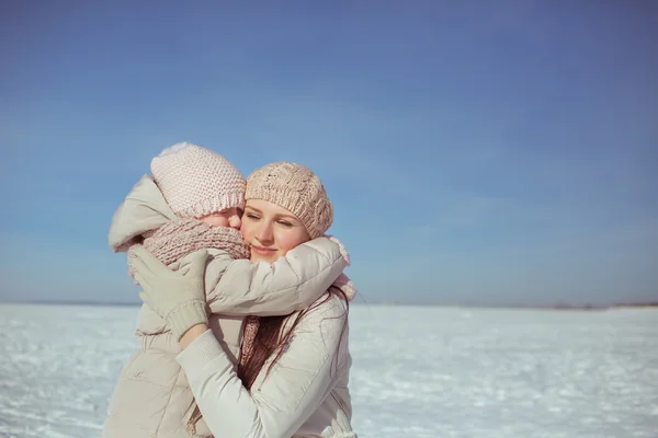 Portrait of little daughter hugs his mother in winter — Stockfoto