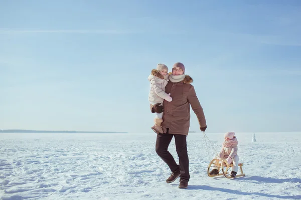 Father sledges his little daughters in winter — Stock Photo, Image