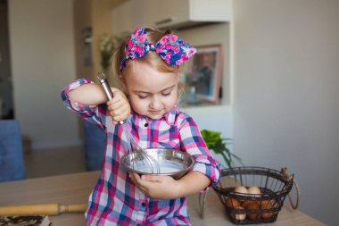 Sevimli küçük kız Kareli gömlekli bir mutfak bir krem kadar kamçı