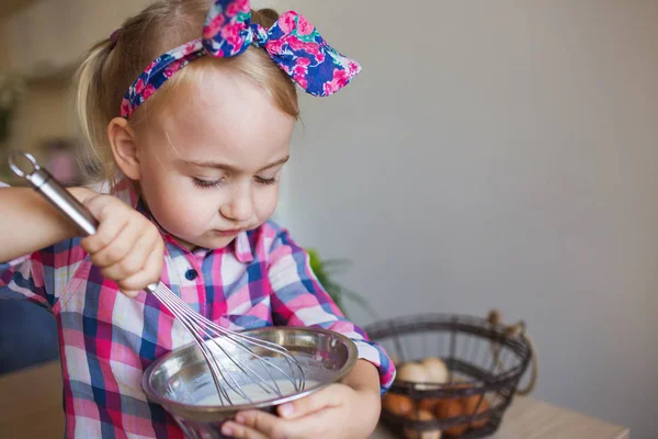 Ritratto di bella bambina in camicia a scacchi frusta una crema a casa — Foto Stock