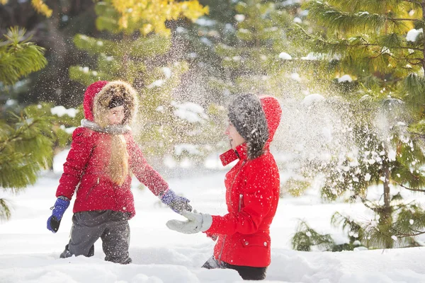 Madre e figlioletta in giacche rosse giocano nella neve nel parco in inverno — Foto Stock