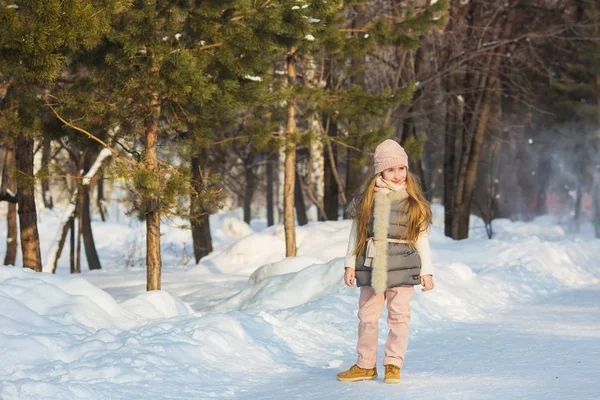 Kleines Mädchen in grauer Jacke steht im Winter in einem Park — Stockfoto