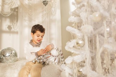 Şirin çocuk Noel ağacı yakınındaki bir yatakta bir büyük cam oyuncakla oynar