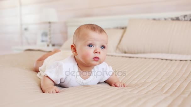 Портрет красивого младенца в белой одежде на кровати дома — стоковое видео