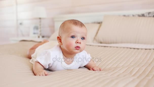 Portrait de joli bébé en vêtements blancs sur un lit à la maison — Video