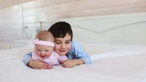 Retrato de lindo hermano con su hermana pequeña en una cama en casa — Vídeos de Stock