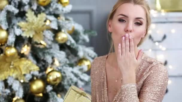 Schöne junge Frau gibt einen Kuss in der Nähe von Weihnachtsbaum — Stockvideo