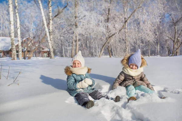Due bambine si siedono e giocano nella neve in un inverno — Foto Stock
