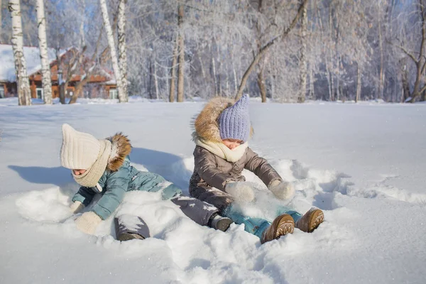 Sorridenti bambine siedono nella neve e sorridono — Foto Stock