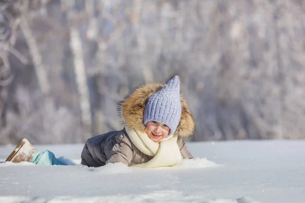 Bambina gioca in cumulo di neve in inverno — Foto Stock