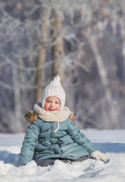 Ritratto di bambina seduta in cumulo di neve nella foresta invernale — Foto Stock