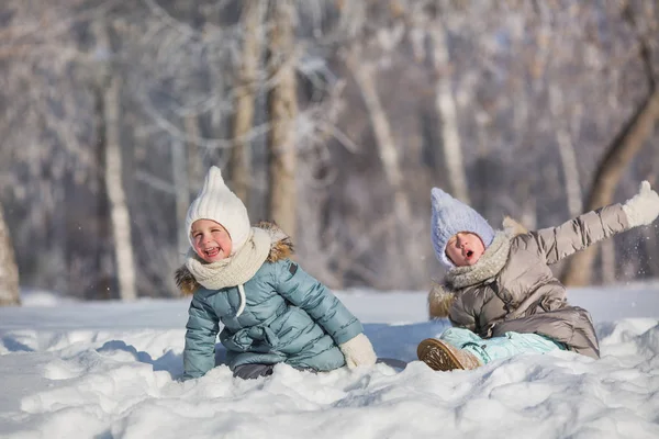 Two little girls sit in snowdrift and make faces in winter — Stock Photo, Image