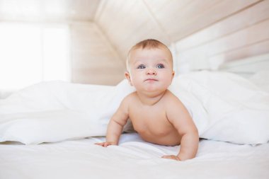 Kızgın ve komik küçük bebek beyaz bir yatakta yatıyor