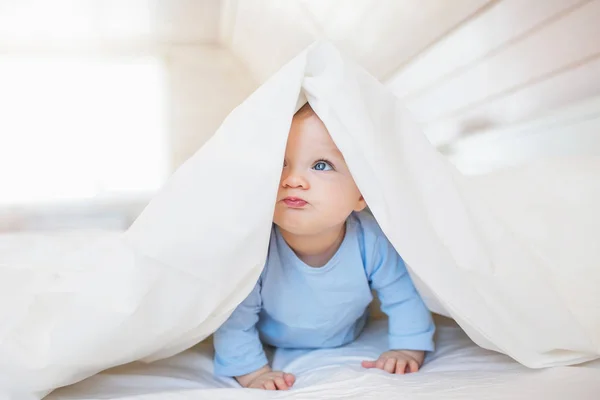 Retrato de divertido bebé se esconde debajo de una manta — Foto de Stock