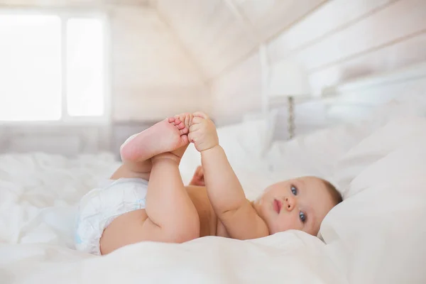 Pequeño bebé en un pañal se encuentra en una cama en el dormitorio — Foto de Stock