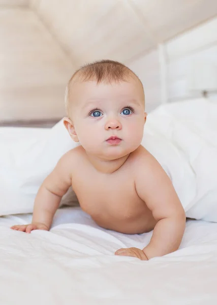 Retrato de bebê jaz em uma cama branca e olha para cima — Fotografia de Stock