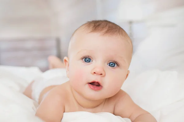 Портрет красивого младенца на белой кровати в спальне — стоковое фото