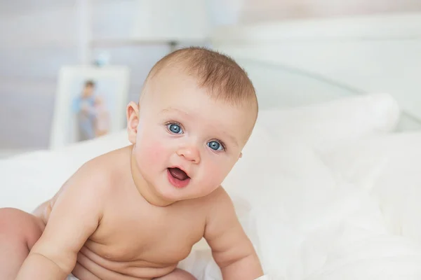 Portret nagie niemowlę uśmiechający się siedzi na łóżku w sypialni — Zdjęcie stockowe