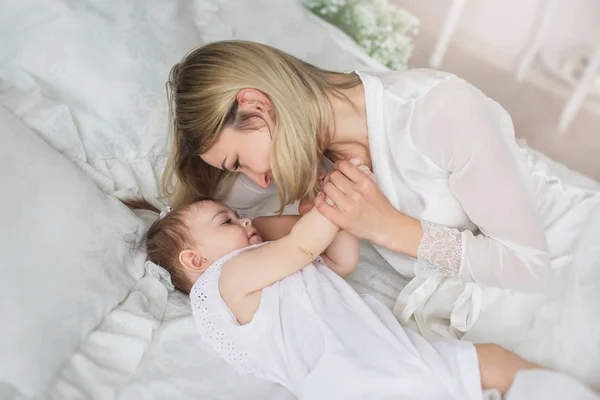 Boldog fiatal anya játszik a kis baba ágyon — Stock Fotó