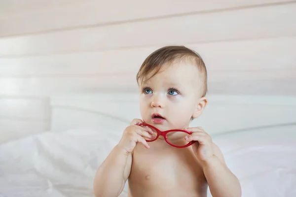 Bonito bebé con anteojos rojos mira hacia arriba — Foto de Stock