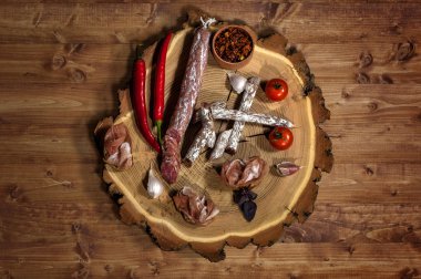 Lezzetli yemekler kırmızı biber, kiraz, tütsülenmiş sosis, tahıl ekmeği, jamon, sarımsak, kurutulmuş domates, fesleğen ahşap arka plan üzerinde ahşap plaka üzerinde.