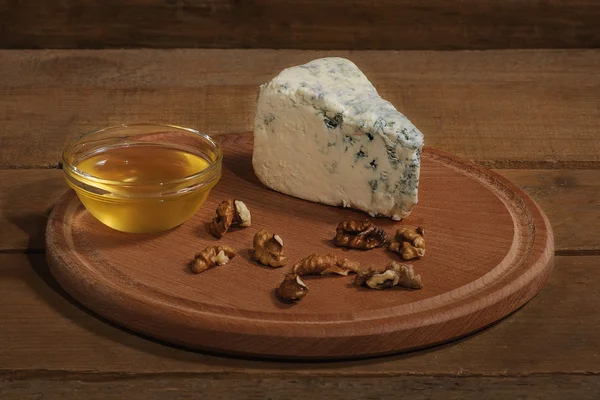 Mavi peynir bal ve ceviz ahşap plaka ve ahşap arka plan ile.