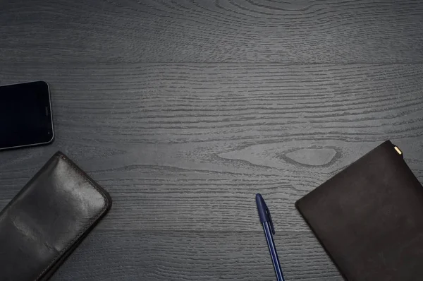 Defter, kalem, cüzdan, cep telefonu ile gri ahşap arka plan