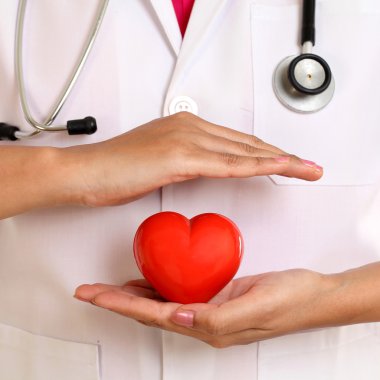 Kadın doktor güzel kırmızı kalp şekli tutan eller 