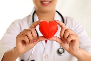 Kadın doktor güzel kırmızı kalp şekli tutan eller