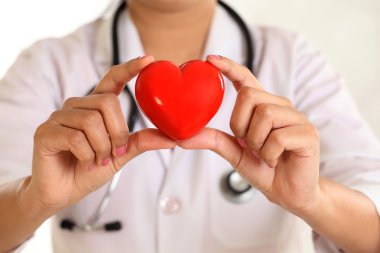 Kadın doktor güzel kırmızı kalp şekli tutan eller