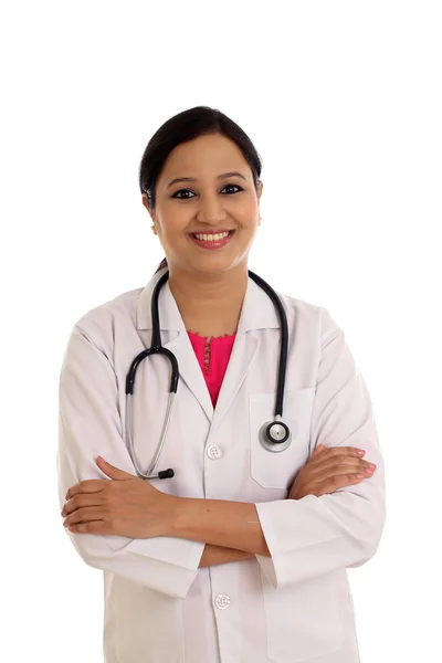 Young female doctor with arms crossed against white background — Stock Photo, Image