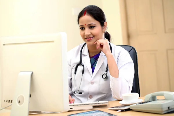 Traditional female doctor holding tablet computer at clinic desk — Stock Photo, Image