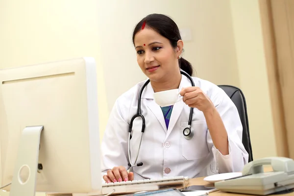 Traditional female doctor holding tablet computer at clinic desk