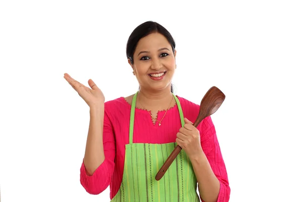 Happy young woman holding kitchen utensil against white backgrou — Stock Photo, Image