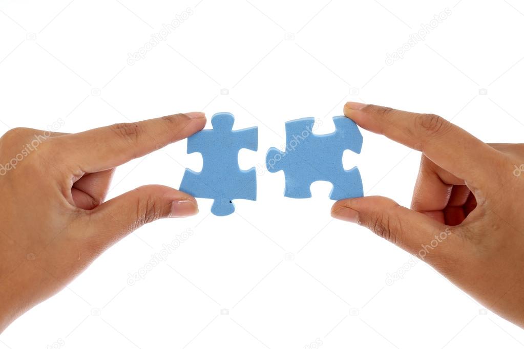 Hands merging two jigsaw puzzle pieces against white background
