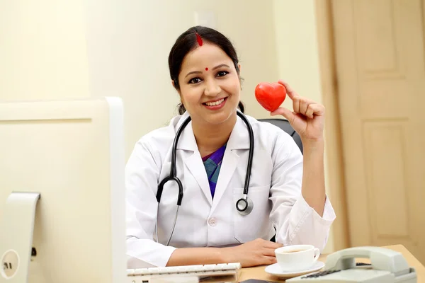 Tineri indian femeie doctor holding roșu forma inimii — Fotografie, imagine de stoc