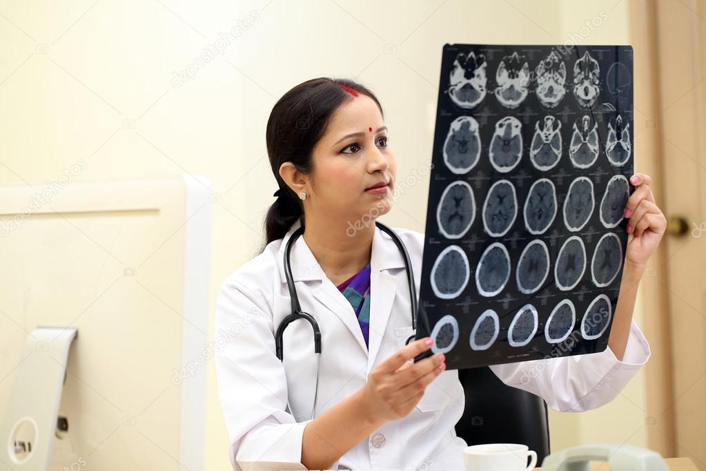 Young Indian female doctor examing a MRI scan report