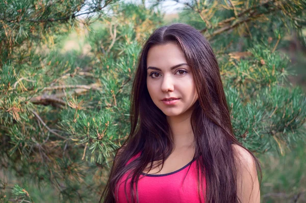 Young beautiful brunette model posing in the sports image of the park against the backdrop trees — Stock Photo, Image