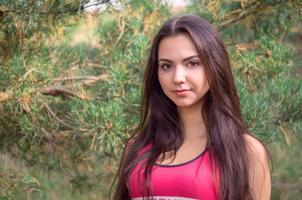 Jovem modelo morena bonita posando na imagem esportiva do parque contra as árvores de fundo — Fotografia de Stock