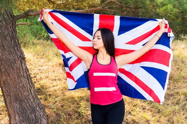 Junge schöne brünette Mädchen posiert mit einer britischen Flagge im Herbst Park — Stockfoto